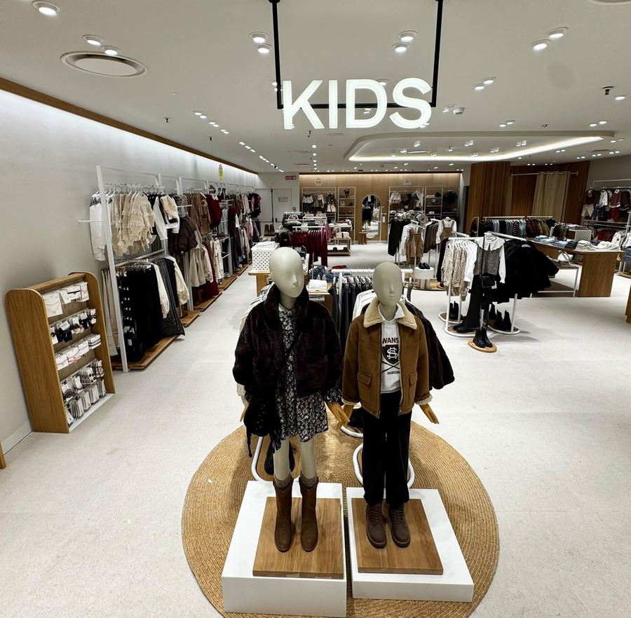 Reparto Mango Kids da Coin a Catania, con insegna luminosa, due manichini e scaffali di abbigliamento per bambini.