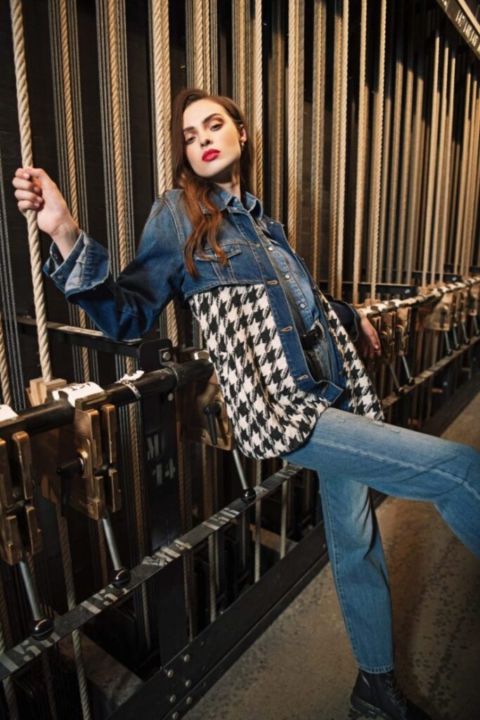 Modella con jeans e giacca in denim e pied-de-poule tra le corde del backstage teatrale