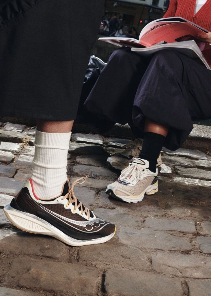 Saucony x Highsnobiety Endorphin Pro 5 marroni e ProGrid Paramount crema, indossate su una pavimentazione in pietra.